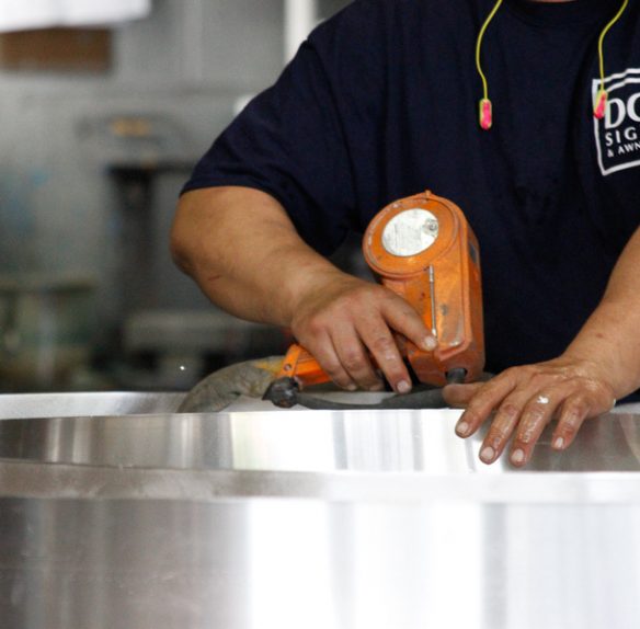 person working on steel fabrication for a sign