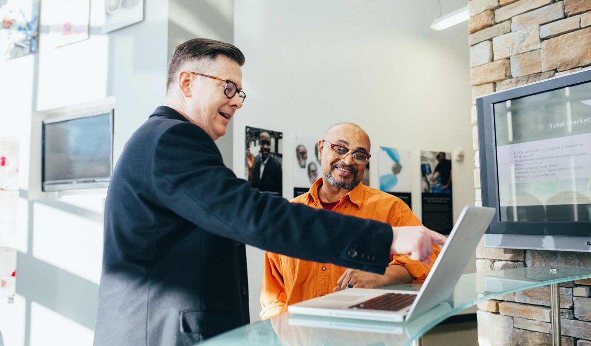 two people pointing at a laptop