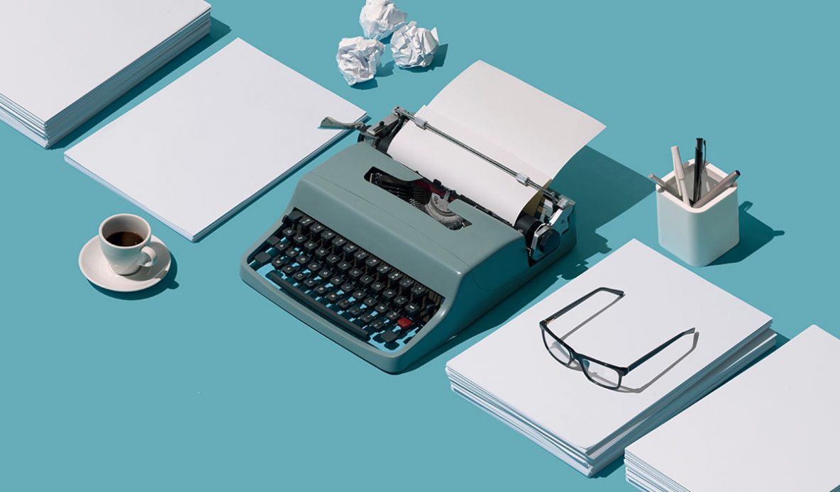 A retro-style typewriter arrainged between stacks of paper