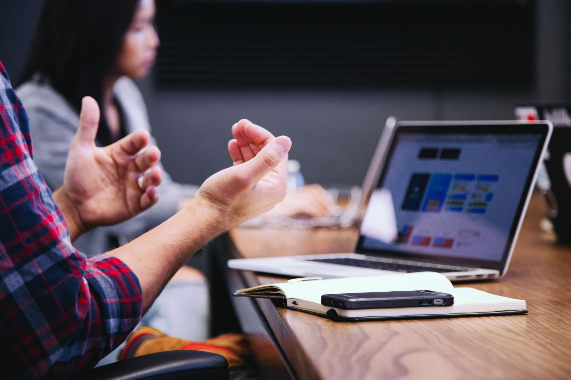 hands-gesturing-in-meeting-next-to-woman-with-laptop-open