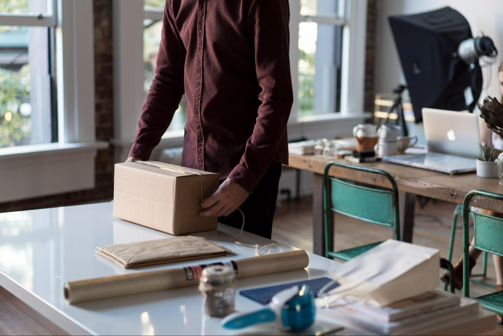 man-wrapping-box-with-rope-in-studio